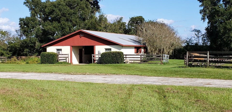 center aisle black barn has storm shutters, a metal roof and storm roll up doors on each end