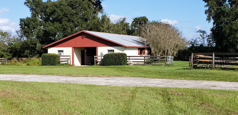 center aisle black barn has storm shutters, a metal roof and storm roll up doors on each end