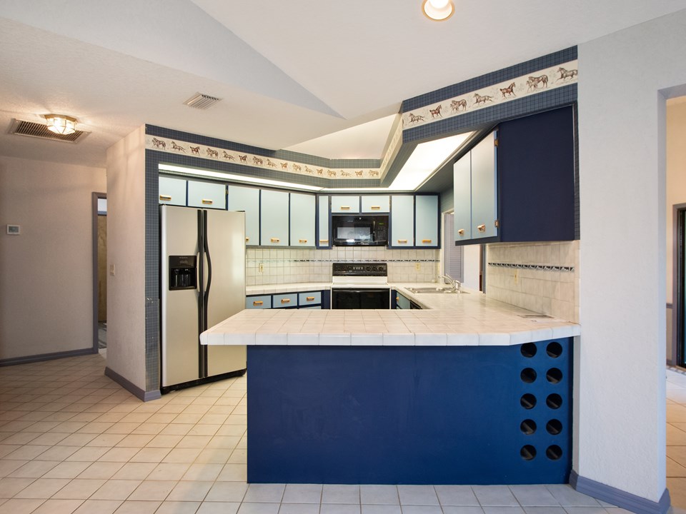 adjoing kitchen has a breakfast bar, complete with appliances