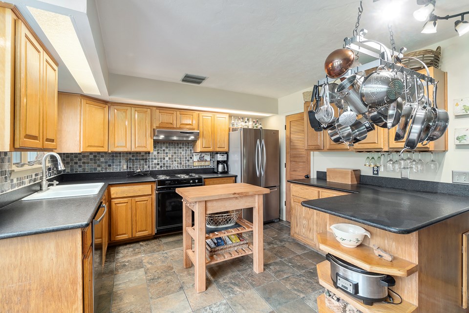wood cabinetry, granite counters, stainless appliances and tiled floors in the kitchen